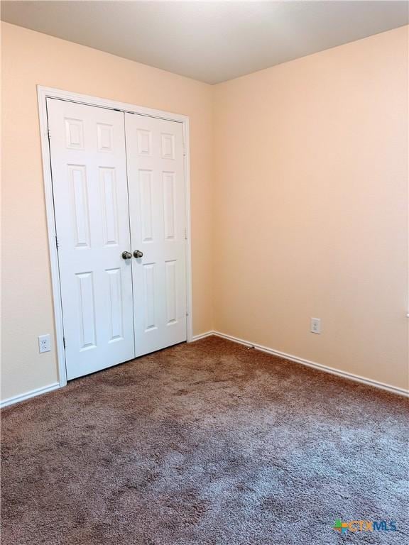 unfurnished bedroom with baseboards, carpet flooring, and a closet