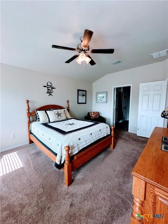 carpeted bedroom with vaulted ceiling, visible vents, baseboards, and ceiling fan