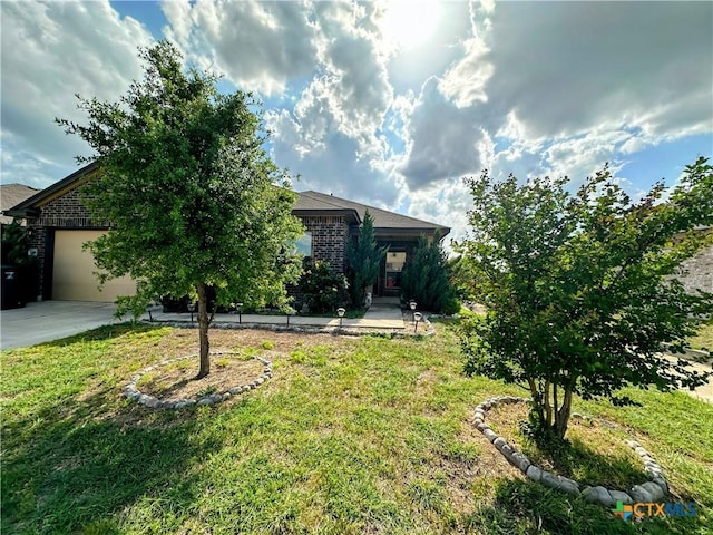 view of property hidden behind natural elements with brick siding, an attached garage, a front yard, and concrete driveway