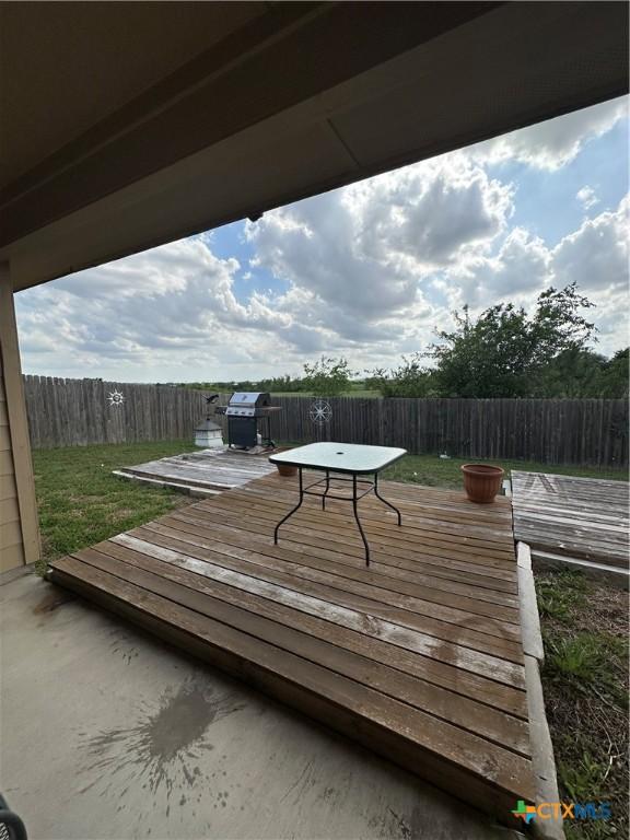 wooden deck featuring area for grilling, outdoor dining area, a fenced backyard, and a lawn