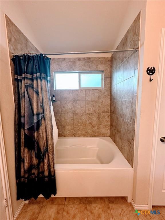 bathroom with vaulted ceiling, tile patterned flooring, and shower / bathtub combination with curtain
