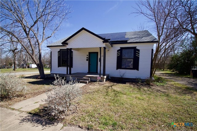 bungalow-style home featuring roof mounted solar panels, a front lawn, and a porch