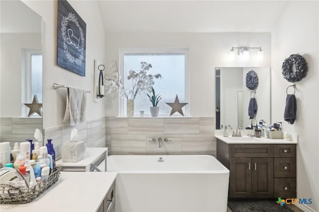 bathroom with vanity, a bathing tub, and tile walls