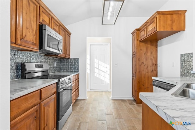 kitchen featuring decorative backsplash, light hardwood / wood-style floors, vaulted ceiling, and appliances with stainless steel finishes