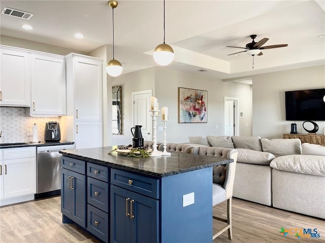 kitchen featuring blue cabinets, hanging light fixtures, stainless steel dishwasher, white cabinets, and backsplash