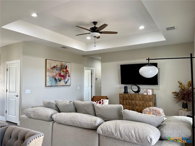 living room featuring ceiling fan and a tray ceiling