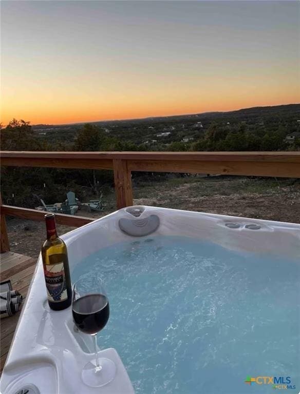 pool at dusk with a hot tub