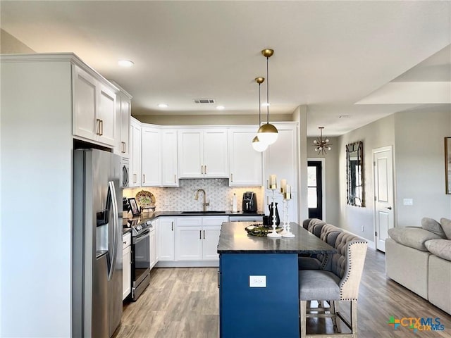 kitchen featuring a breakfast bar, sink, hanging light fixtures, stainless steel appliances, and white cabinets