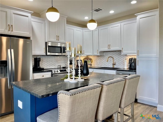 kitchen featuring pendant lighting, appliances with stainless steel finishes, sink, and white cabinets