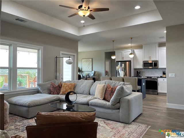 living room featuring ceiling fan, a tray ceiling, and hardwood / wood-style floors