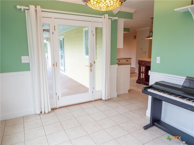 interior space with ornamental molding, light tile patterned floors, and a wainscoted wall