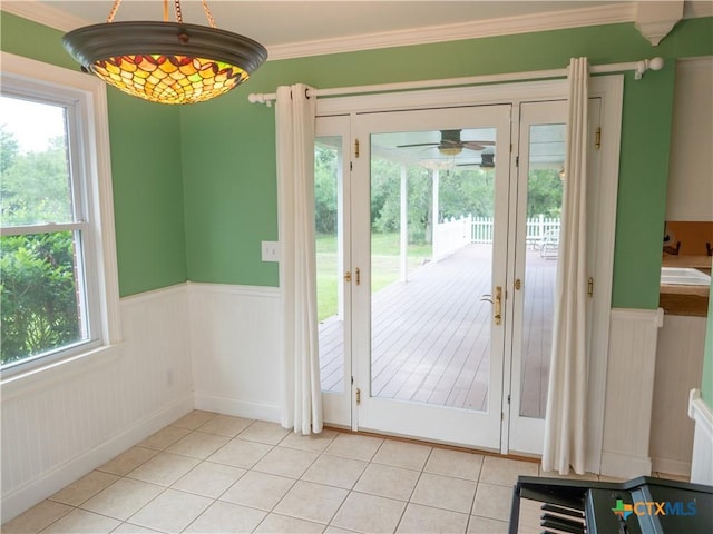 doorway to outside featuring light tile patterned floors, wainscoting, and a wealth of natural light