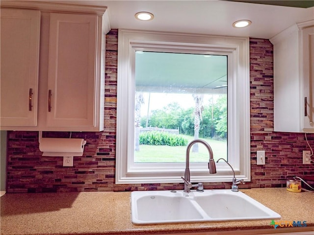 kitchen with backsplash, a sink, light countertops, recessed lighting, and white cabinetry