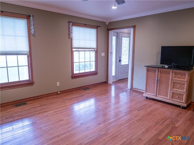 unfurnished living room featuring baseboards, visible vents, ornamental molding, and light wood finished floors
