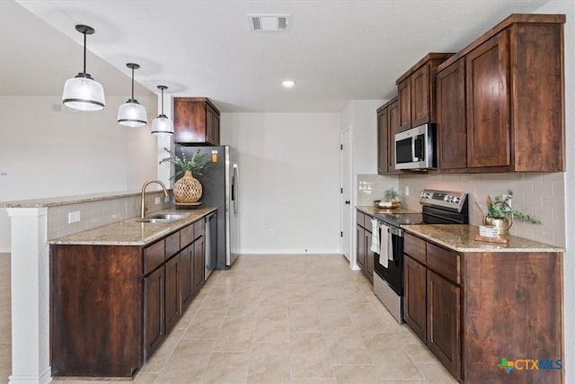 kitchen featuring light stone countertops, pendant lighting, appliances with stainless steel finishes, and sink