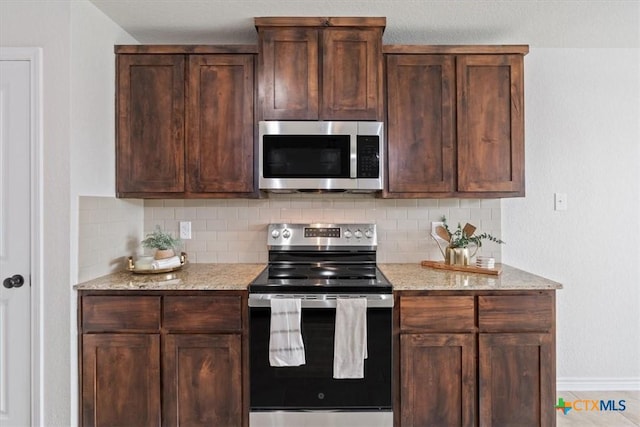 kitchen with light stone counters, backsplash, and appliances with stainless steel finishes