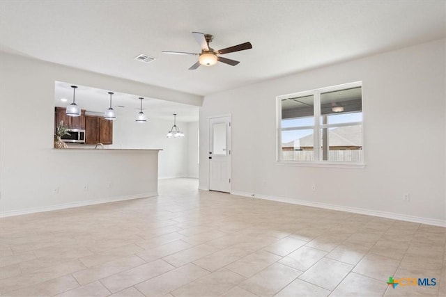 unfurnished living room with ceiling fan with notable chandelier and light tile patterned floors