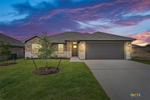 view of front of property featuring a lawn, central AC unit, and a garage