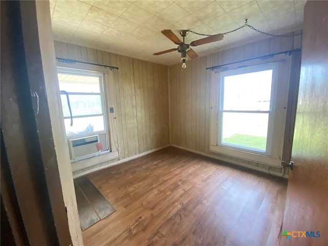 empty room featuring a ceiling fan, baseboards, a healthy amount of sunlight, and wood finished floors