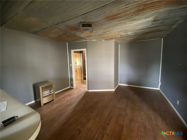interior space featuring heating unit, baseboards, and wood finished floors