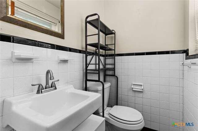 809 S 13th St, Copperas Cove, TX 76522 - half bathroom featuring tile walls, a sink, toilet, and a wainscoted wall