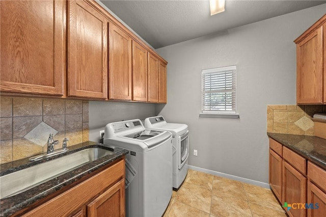 clothes washing area with washer and dryer, sink, light tile patterned floors, and cabinets