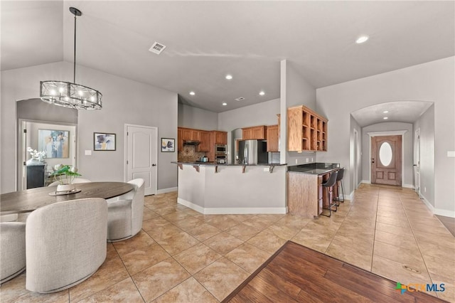 kitchen featuring lofted ceiling, decorative light fixtures, a kitchen breakfast bar, and appliances with stainless steel finishes