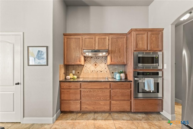 kitchen with stainless steel appliances, light tile patterned floors, and backsplash