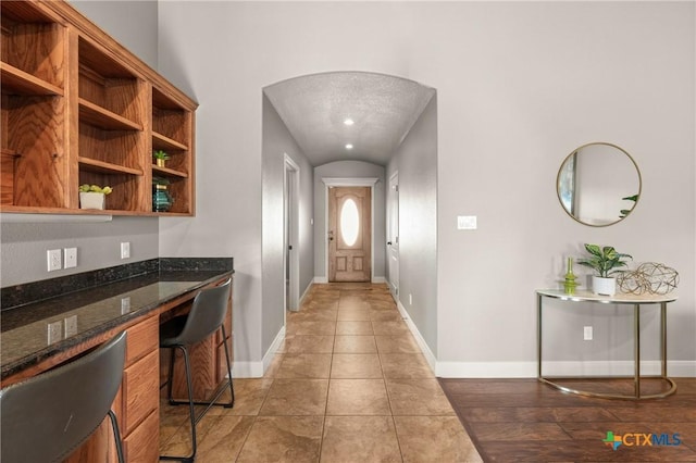 interior space featuring light tile patterned floors, built in desk, and dark stone counters