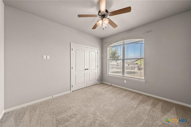 unfurnished bedroom featuring ceiling fan, a closet, and light carpet