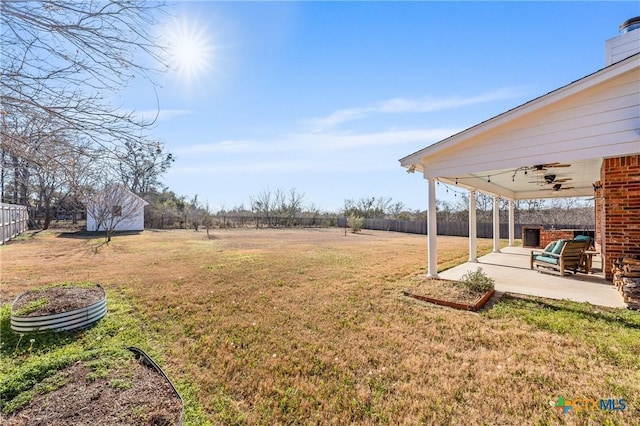 view of yard featuring ceiling fan, a shed, a patio, and a rural view