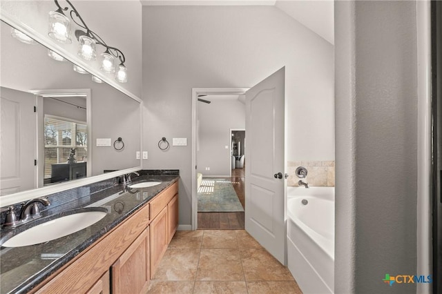 bathroom with tile patterned flooring, vanity, lofted ceiling, and a tub to relax in