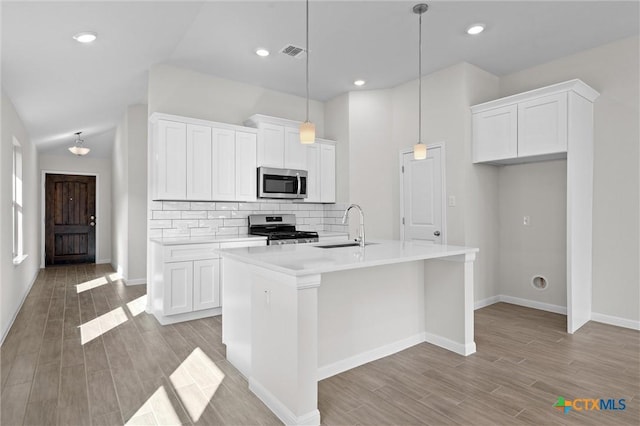 kitchen with appliances with stainless steel finishes, white cabinetry, a kitchen island with sink, and sink