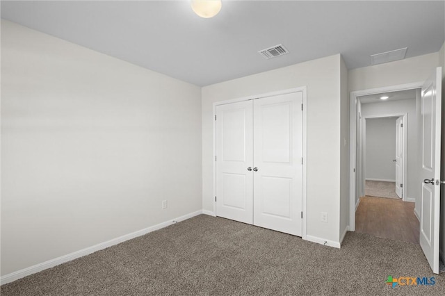 unfurnished bedroom featuring dark carpet and a closet