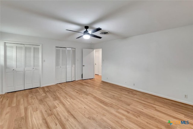 unfurnished bedroom with ceiling fan, multiple closets, and light hardwood / wood-style flooring