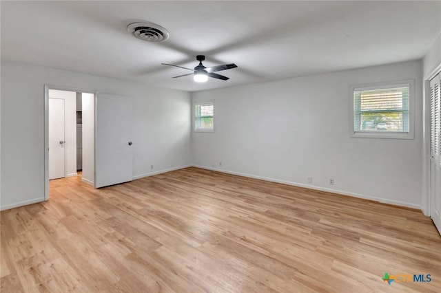 empty room with ceiling fan, a wealth of natural light, and light hardwood / wood-style flooring