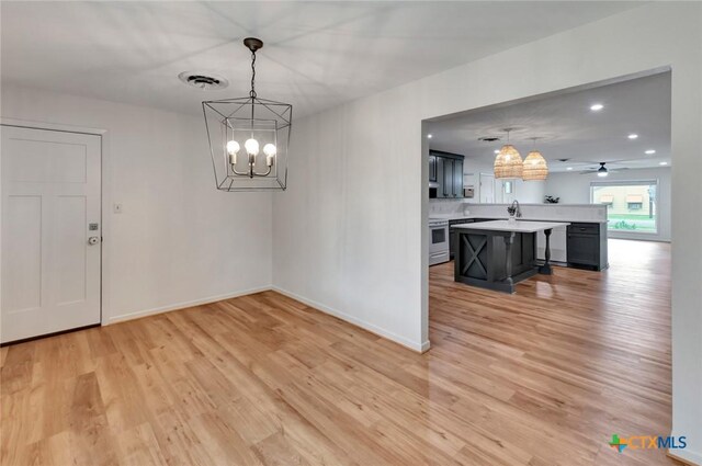 unfurnished dining area with light wood-type flooring and ceiling fan with notable chandelier