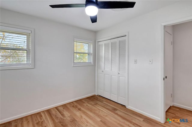 unfurnished bedroom with ceiling fan, multiple windows, a closet, and light hardwood / wood-style flooring