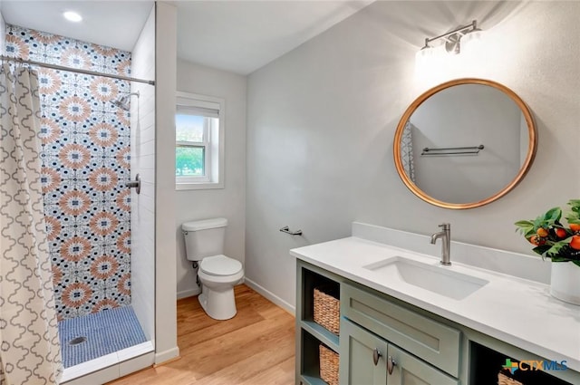 bathroom with a shower, hardwood / wood-style flooring, toilet, and vanity