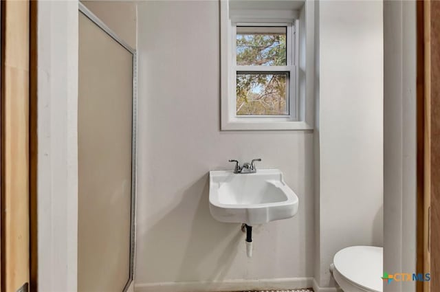 bathroom featuring sink, toilet, and an enclosed shower