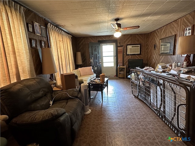 living room featuring a ceiling fan, a wall mounted AC, wooden walls, and dark floors