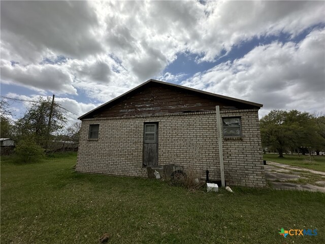 view of home's exterior with brick siding and a yard