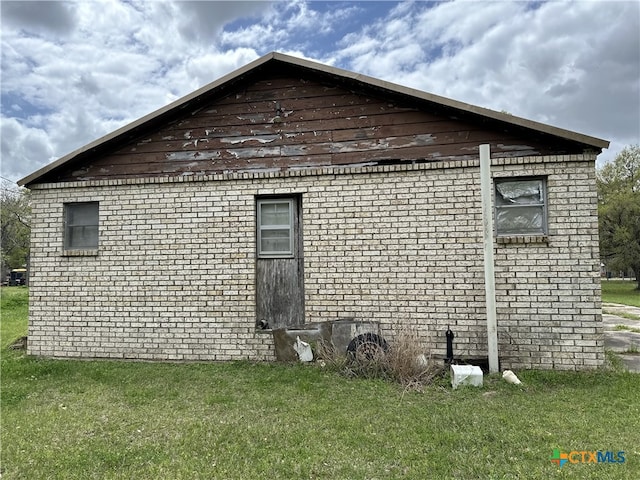 view of side of property with a lawn and brick siding
