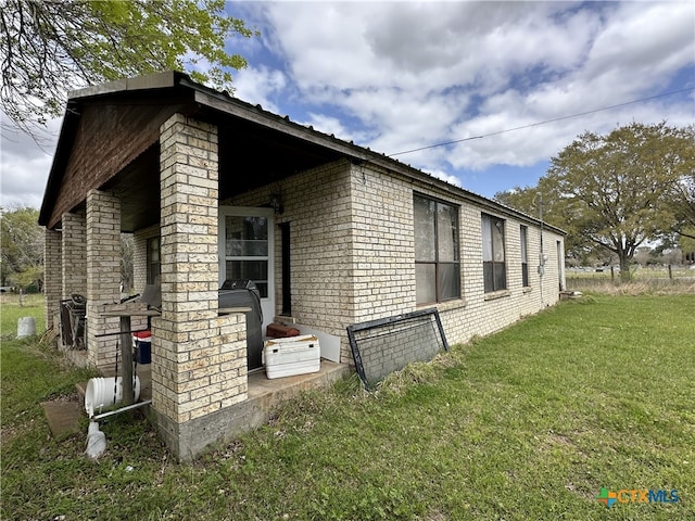 view of side of home featuring a lawn and brick siding