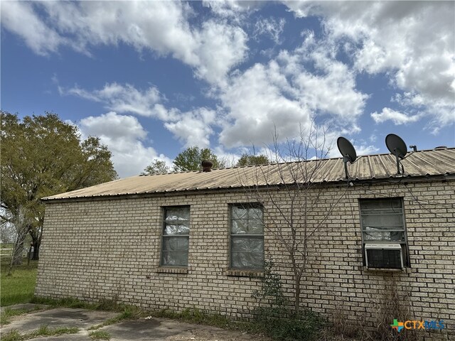 view of side of property with brick siding and metal roof