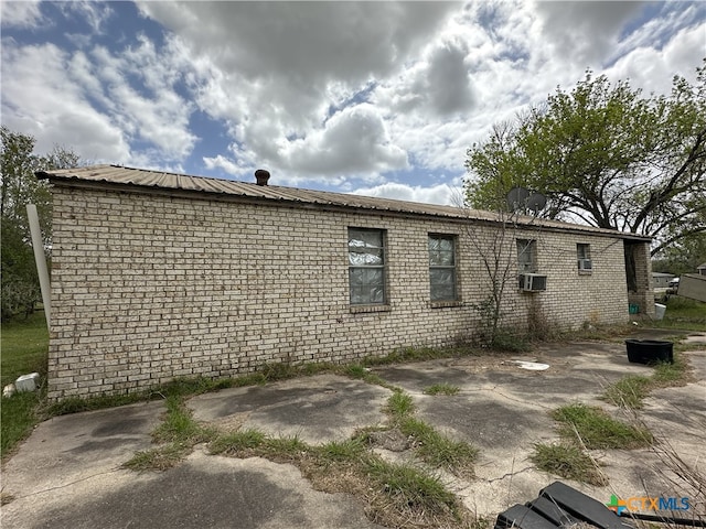 back of property featuring brick siding, metal roof, and a patio