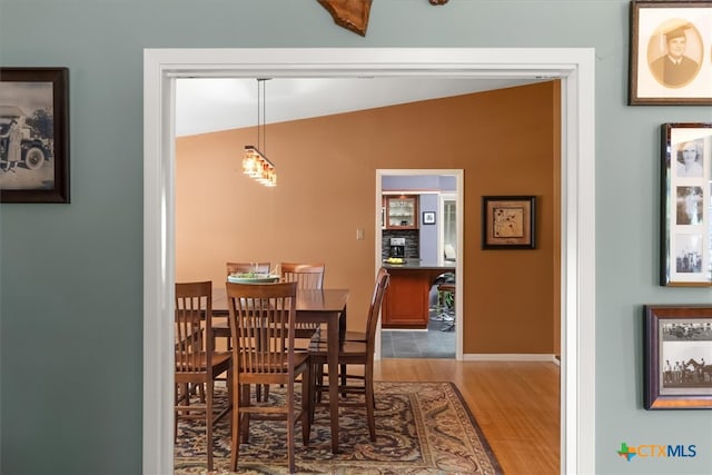 dining space with wood-type flooring and vaulted ceiling