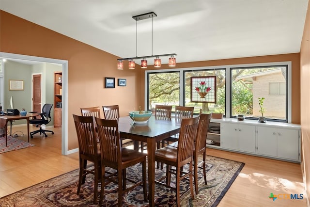 dining area featuring light wood-type flooring and vaulted ceiling