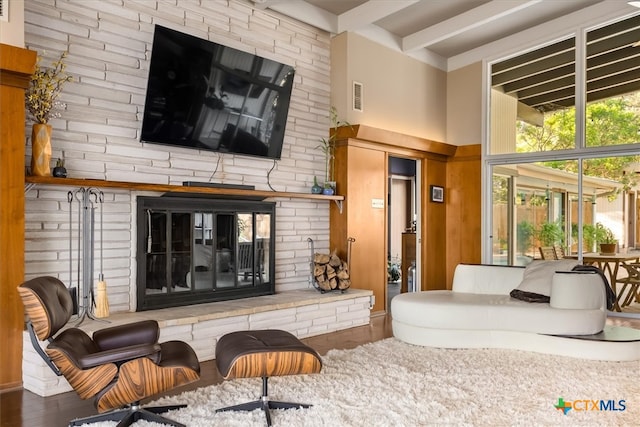 living room featuring a towering ceiling, a fireplace, beamed ceiling, and dark hardwood / wood-style floors