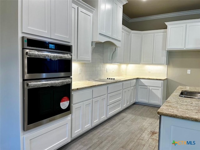 kitchen with light wood-type flooring, backsplash, ornamental molding, double oven, and white cabinets